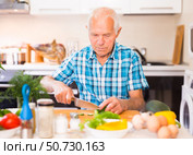 senor man preparing fresh vegetable salad at home in the kitchen. Стоковое фото, фотограф Татьяна Яцевич / Фотобанк Лори