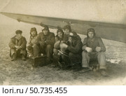 Группа советских летчиков под крылом самолета в дождливую погоду, 1950 год. Петр Шевченко ведет разбор хронометража. Стоковое фото, фотограф Retro / Фотобанк Лори