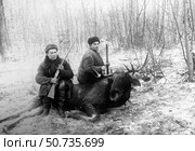Охотники с ружьями сидят на убитом лосе в зимнем лесу. Стоковое фото, фотограф Retro / Фотобанк Лори