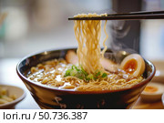 Chopsticks lifting steaming noodles from bowl of ramen. Стоковое AI-изображение, AI-художник Иван Рябоконь / Фотобанк Лори