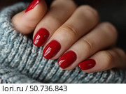 Woman showing red polished fingernails on soft woolen sweater. Стоковое AI-изображение, AI-художник Иван Рябоконь / Фотобанк Лори