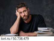 Tired businessman resting head on hand at desk with piles of paperwork. Стоковое AI-изображение, AI-художник Юрий Поздников / Фотобанк Лори