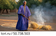 African farmer burning hay in rural village during sunset. Стоковое AI-изображение, AI-художник Юрий Поздников / Фотобанк Лори