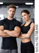 Confident personal trainers posing with crossed arms in gym. Стоковое AI-изображение, AI-художник Юрий Поздников / Фотобанк Лори