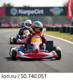 Children driving go-karts on a sunny day, realistic photo style, on outdoor asphalt track, concept of youth motor sport competition. Стоковое AI-изображение, AI-художник Александра Рублева / Фотобанк Лори