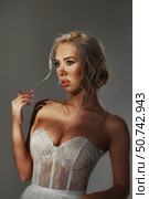 Elegant Woman In Corset Gazing With Gentle Expression, Against Gray Backdrop. Стоковое фото, фотограф Aleksandr Golubev / Фотобанк Лори