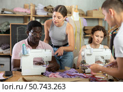 Young seamstress mentoring fashion students in garment construction class. Стоковое фото, фотограф Яков Филимонов / Фотобанк Лори