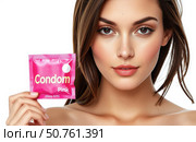 Young attractive woman holding bright pink condom package smiling slightly on white background showcasing modern sexual health awareness contraception safety and feminine empowerment concept. Стоковое AI-изображение, AI-художник Павел Муравьев / Фотобанк Лори