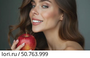 Woman Holding a Red Apple, Confidently Gazing at the Camera in a Warm Setting, Embodying Health and Wellness. Стоковое AI-видео, аниматор Sergey Grishin / Фотобанк Лори