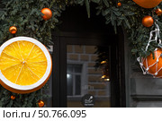 Happy New Year 2026. Mandarins in a string bag and Christmas tree decorations on the streets of Moscow. The concept of preparing decorations and ornaments for Christmas. Стоковое фото, фотограф Photojuli / Фотобанк Лори