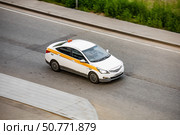White taxi speeding along a city street, captured in motion. The dynamic movement highlights urban transportation, featuring driver focused and alert amidst city traffic. Редакционное фото, фотограф Константин Григорьев / Фотобанк Лори