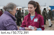 Nurse giving medical supplies to elderly woman in refugee camp. Стоковое AI-видео, аниматор Юрий Поздников / Фотобанк Лори