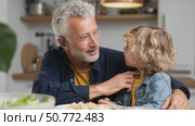 Grandfather wearing hearing aid interacting with grandson at lunch. Стоковое AI-видео, аниматор Юрий Поздников / Фотобанк Лори