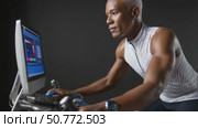 Determined senior athlete cycling on stationary bike with performance tracking software. Стоковое AI-видео, аниматор Юрий Поздников / Фотобанк Лори