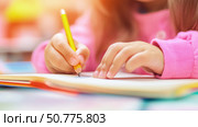 A close-up of a child’s hand writing in a notebook with a pencil. Стоковое AI-изображение, AI-художник Катерина Бондарец / Фотобанк Лори