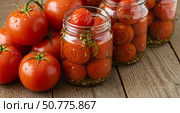 Fresh red tomatoes with water drops and jars of preserved tomatoes. Home canning for winter storage concept. Стоковое AI-изображение, AI-художник Анжелика Самсонова / Фотобанк Лори
