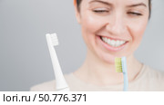 Happy woman compares a toothbrush with an electric one. The girl chooses oral hygiene products. Стоковое фото, фотограф Михаил Решетников / Фотобанк Лори