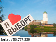 Сувенир «Я люблю Выборг» на фоне Башни Святого Олафа в Выборгском замке на Замковом острове в городе Выборг Ленинградской области, Россия. Стоковое фото, фотограф Яна Проничева / Фотобанк Лори