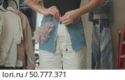 A young, slim woman is trying on a skirt that she created during a masterclass on crafting and decorating denim clothing. Стоковое видео, видеограф Strunov David / Фотобанк Лори