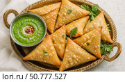 Golden samosas with green chutney served on a decorative platter. Стоковое AI-изображение, AI-художник Андрей Бажанов / Фотобанк Лори