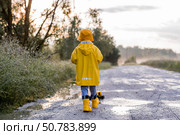 A boy in yellow rubber boots and a raincoat runs through puddles, having fun and playing with a remote-controlled car after it rains. Summer and autumn holidays. A happy childhood. Стоковое фото, фотограф Photojuli / Фотобанк Лори