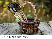 Wooden arrows resting in a handmade basket on a rustic wooden table. Стоковое AI-изображение, AI-художник Иван Рябоконь / Фотобанк Лори