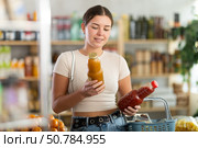Girl hold packages bottles and choose consider juice in store. Стоковое фото, фотограф Яков Филимонов / Фотобанк Лори