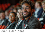 A modern business scene depicting a group of young professionals sitting in an audience during a conference or business event. In the foreground, a smiling man in glasses and a business suit radiates confidence and positivity. Around him are participants listening attentively or communicating with each other. The image conveys an atmosphere of productive communication, inspiration and professional development. Suitable for the topics of leadership, business, education, networking and career growth. Стоковое AI-изображение, AI-художник Анна Кривицкая / Фотобанк Лори