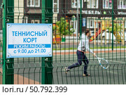 Мужчина играет на теннисном корте во дворе жилого комплекса. Отдых горожан на спортивной площадке. Стоковое фото, фотограф Евгений Зимин / Фотобанк Лори