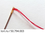 Close-up of metal needle for visually impaired people with special gold plated needle-eye and red thread on white background. Top view, copy space, flat lay, macro, mockup. Стоковое фото, фотограф Виктория Катьянова / Фотобанк Лори