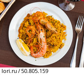Paella made of rice and different seafood served in plate with table appointments. Стоковое фото, фотограф Яков Филимонов / Фотобанк Лори