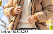 Stylish individual zips up a cozy brown winter jacket on a sunny day outdoors. Стоковое AI-изображение, AI-художник Сергей Толмачёв / Фотобанк Лори