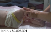 Slow-motion video of a six-month-old baby receiving a leg massage to improve right hip joint mobility. Pediatric physiotherapy concept. Стоковое видео, видеограф Татьяна Степанищева / Фотобанк Лори