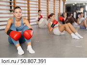 Girls in boxing gloves are sitting on floor, doing abdominal exercise and working with hands. Стоковое фото, фотограф Яков Филимонов / Фотобанк Лори