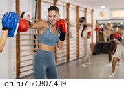 Woman works out strength and speed of boxing punch mitts with help of partner in boxing paws. Стоковое фото, фотограф Яков Филимонов / Фотобанк Лори