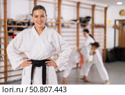 Female coach in white kimono smiles affably, students sparring in background. Стоковое фото, фотограф Яков Филимонов / Фотобанк Лори