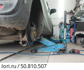 Автомобиль поднят домкратом, замена колеса в гараже. The car is filled with a jack, the wheel is replaced in the garage. Стоковое фото, фотограф Денис Баданин / Фотобанк Лори