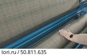A woman works on a fabric inspection machine in a garment factory, on which a checkered fabric is wound, a person's hand touches the fabric. Стоковое видео, видеограф Дмитрий Нечаев / Фотобанк Лори