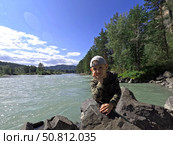 Ребенок задумчиво позирует на фоне горной реки Катунь в Горном Алтае. A child poses thoughtfully against the backdrop of the Katun Mountain River in Gorny Altai. Стоковое фото, фотограф Денис Баданин / Фотобанк Лори