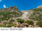 Steep rocky mountains with a prominent scree slope, scattered boulders, green shrubs, clear blue sky, perfect for mountaineering, hiking, trekking, outdoor adventure, and nature exploration. Стоковое фото, фотограф Андрей Ка / Фотобанк Лори