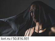 Woman in a black veil with dark makeup and an earring in her nose. Halloween Dead Bride Costume. Portrait of an ominous witch in front of a coven in a dark studio. Стоковое фото, фотограф Михаил Решетников / Фотобанк Лори