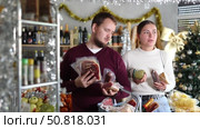 Joyful couple in Santa hats choose products for Christmas dinner. Man and woman with food basket shopping in grocery store. Стоковое видео, видеограф Яков Филимонов / Фотобанк Лори