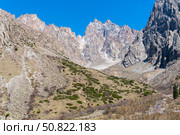 Ala-Archa Park, Steep rocky mountains rise sharply under a vivid blue sky. Barren slopes. Alpine terrain, creating a perfect environment for trekking, climbing, and outdoor adventure activities. Стоковое фото, фотограф Андрей Ка / Фотобанк Лори