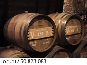 Stacked oak barrels with wine, Inkerman winery interior (2018 год). Редакционное фото, фотограф EugeneSergeev / Фотобанк Лори