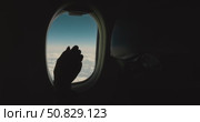 Hand in closes airplane window shade, blocking view of blue sky and clouds, inside aircraft cabin, passenger seatback and porthole, realistic travel scene showing end of journey or landing preparation. Стоковое видео, видеограф Сергей Тимофеев / Фотобанк Лори