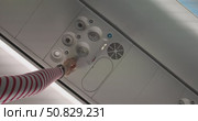 Airplane passenger adjusting overhead air vent nozzle, close up of aircraft cabin control panel with ventilation, call buttons, seat belt and no smoking signs, passenger hand, concept travel. Стоковое видео, видеограф Сергей Тимофеев / Фотобанк Лори