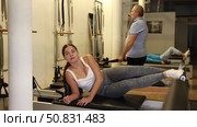 Positive calm young woman doing lower back exercises while lying on Pilates bed in wellness center. Стоковое видео, видеограф Яков Филимонов / Фотобанк Лори