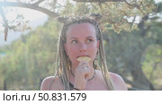Girl with dreadlocks eats a cracker on the street. Стоковое видео, видеограф German Zvyagin / Фотобанк Лори