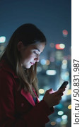 Beautiful and inspiring young woman over epic night city background. Millennial female with screen lit face, doomsurfing and doomscrolling, cool trendy teenager looking woman. Smartphone application. Стоковое AI-видео, аниматор Sergey Grishin / Фотобанк Лори