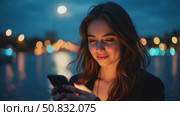 Beautiful and inspiring young woman over epic night city background. Millennial female with screen lit face, doomsurfing and doomscrolling, cool trendy teenager looking woman. Smartphone application. Стоковое AI-видео, аниматор Sergey Grishin / Фотобанк Лори